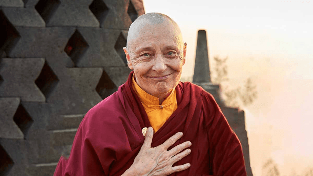 Jetsunma Tenzin Palmo, a renowned female Buddhist teacher in Tibetan Buddhism, wearing maroon and yellow robes with her hand on her chest. She is celebrated for breaking barriers for women in Buddhism, inspiring equality, and honoured on International Womenβs Day.